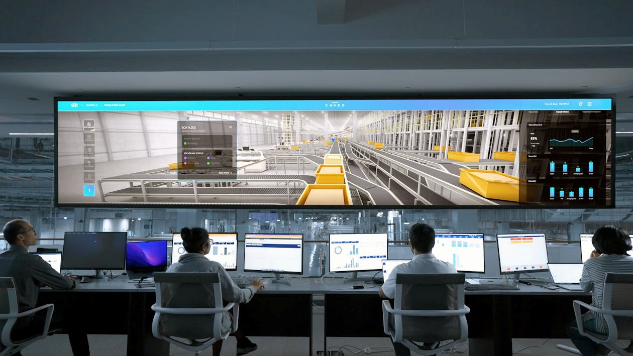 men and women sitting in front of computers and a large screen
